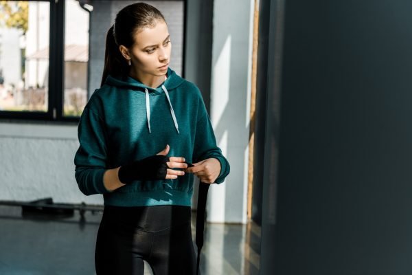 attractive sportswoman putting on sport gloves at gym